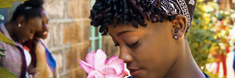 A young woman smelling a large pink bloom.