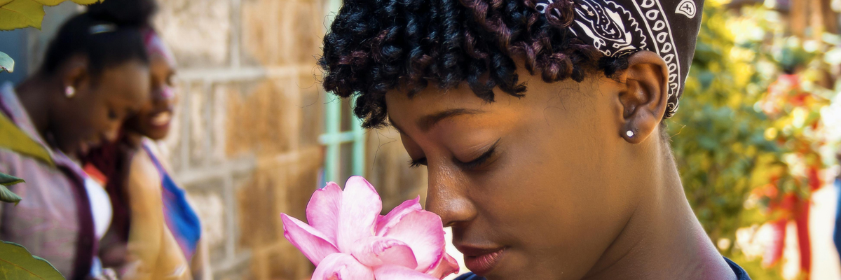 A young woman smelling a large pink bloom.