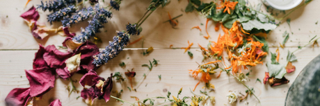 Colourful, dried flowers such as sprigs of lavender and rose petals on a wooden table