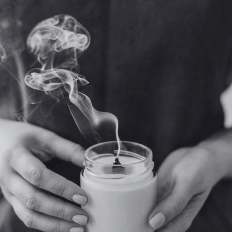 Clearance fragrance oils and accessories - person holding candle that has been blown out.
