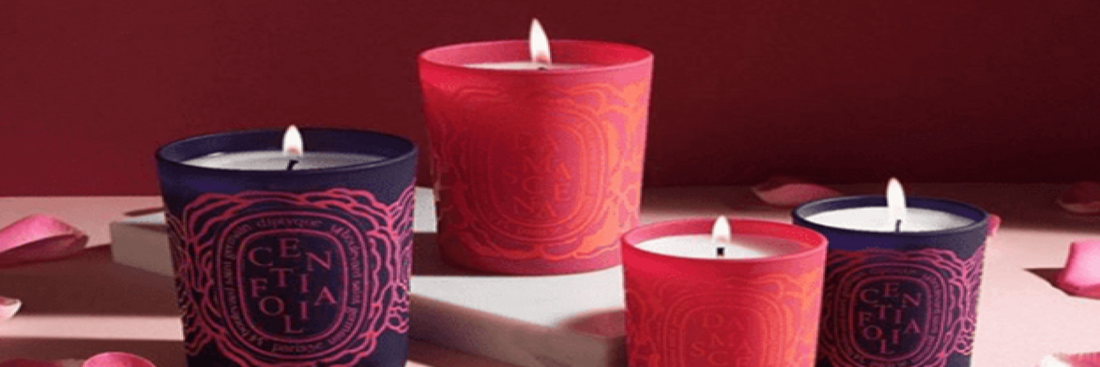 A display of purple and pink branded candles among rose petals. Sourced from Candle Delirium