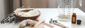 A worktop with a bowl of wax, candle wicks, oil and jug ready for candle making