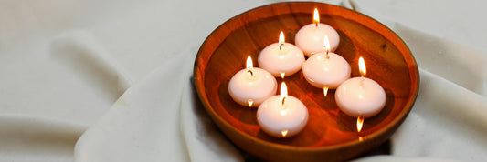A wooden bowl containing a series of circular floating candles. Source: Pexels