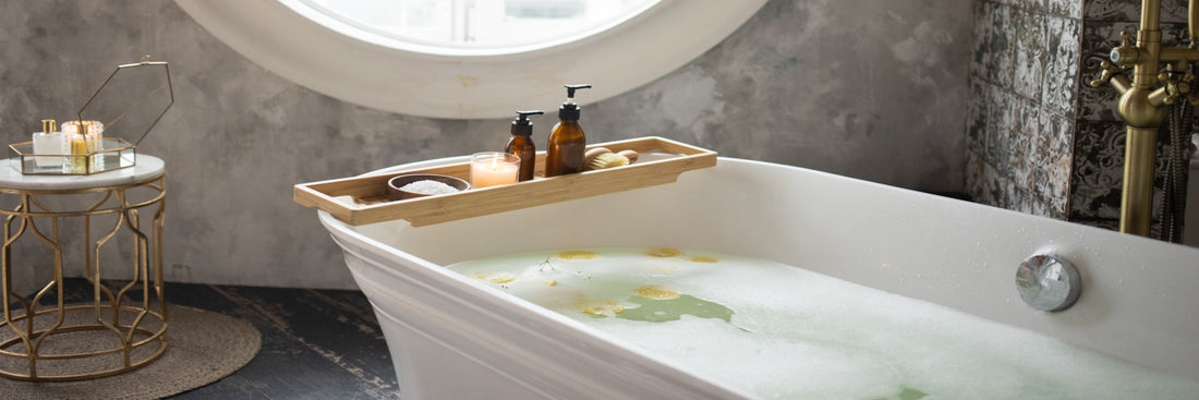 Tranquil bathroom scene with a candle burning on a bath dray above a bubble bath.
