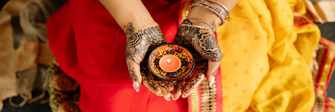 An overhead shot of a woman with henna tattoos holding a bright candle. Sourced from Pexels.
