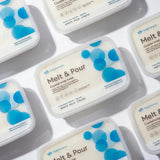 Multiple containers of Melt & Pour crystal soap base with blue and white labels on a light gray background.