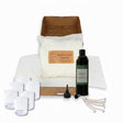Candle-making kit with wicks, containers, and a bottle of fragrance oil on a white background