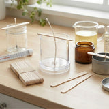 Wooden wick holders and glass containers on a wooden surface with a window in the background