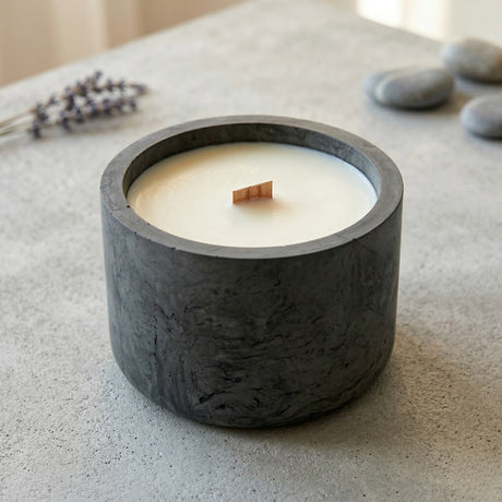 Refilable Candle in a dark stone holder on a light surface with lavender and stones in the background